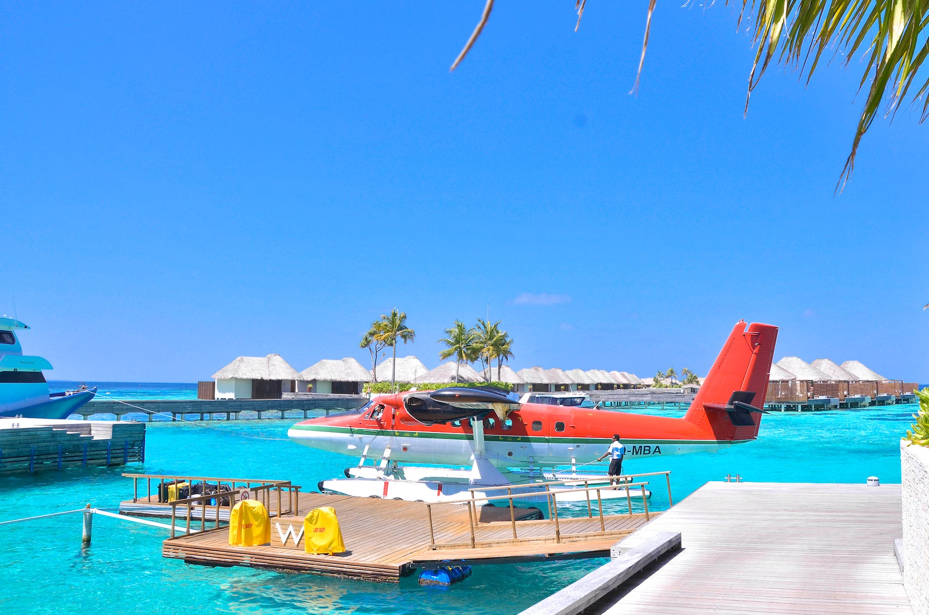 white and red seaplane on body of water